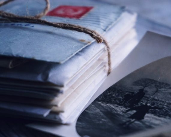 A close-up of vintage letters tied with twine alongside an old black and white photograph.